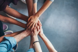 A varied group of people putting their hands into a circle